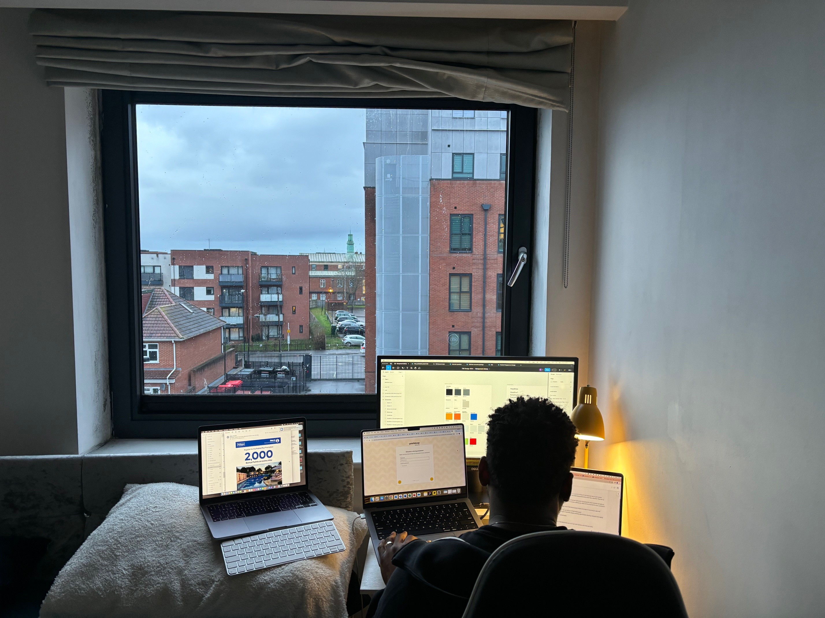 Image of Emmanuel sitting while operating three computers